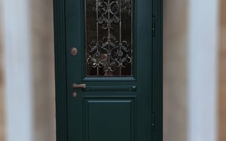 стальная дверь в коттедж с кованой решеткой и стеклом, установлена в частном коттедже